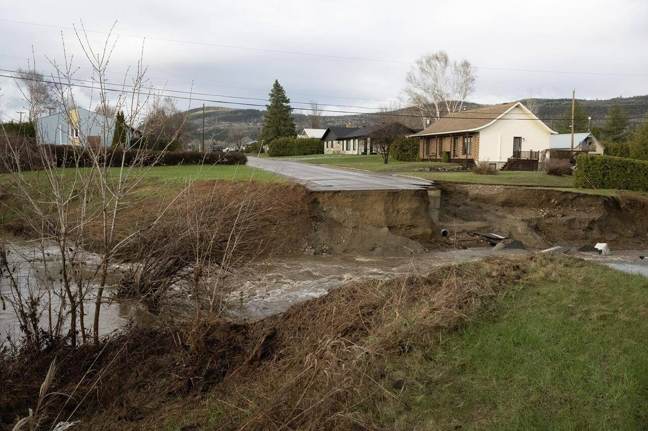 A neighborhood is cut off from the city as a flooded river took out the bridge on Monday, May 1, 2023 in Baie-Saint-Paul, Quebec. Funerals for two Quebec volunteer firefighters who died earlier this month during flash floods in the Charlevoix region will be private affairs. THE CANADIAN PRESS/Jacques Boissinot
