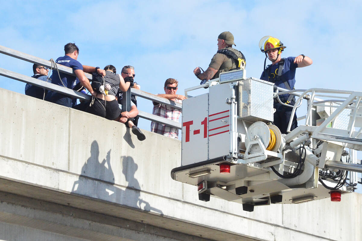 A woman clinging to the outside railings of the 204th Street Overpass in Langley City was rescued and brought to the ground on Thursday during afternoon rush hour. (Matthew Claxton/Langley Advance Times)