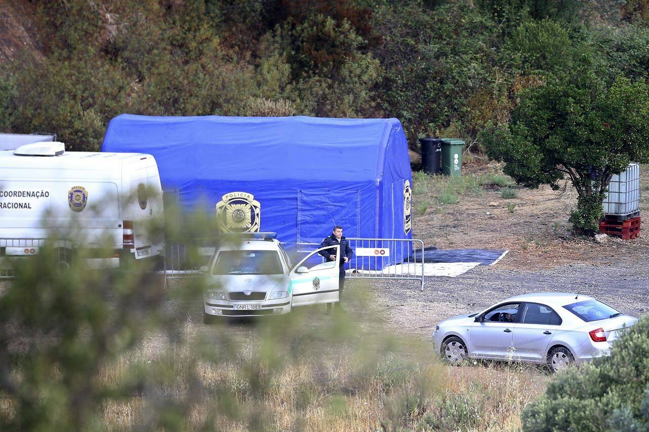 A police officer stands by a car and a tent near Barragem do Arade, Portugal, Tuesday May 23, 2023. Portuguese police said they will resume searching for Madeleine McCann, the British toddler who disappeared in the country's Algarve region in 2007, in the next few days. Portugal's Judicial Police released a statement confirming local media reports that they would conduct the search at the request of the German authorities and in the presence of British officials. (AP Photo/Joao Matos)