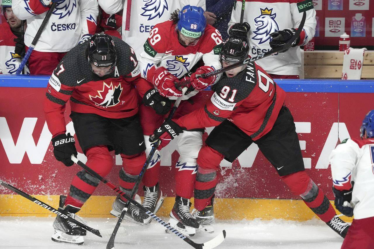 Milan Lucic, left, and Adam Fantilli, right of Canada fight for a puck with Daniel Vozenilek of Czechia during the group B match at the ice hockey world championship in Riga, Latvia, Tuesday, May 23, 2023. THE CANADIAN PRESS/AP-Roman Koksarov