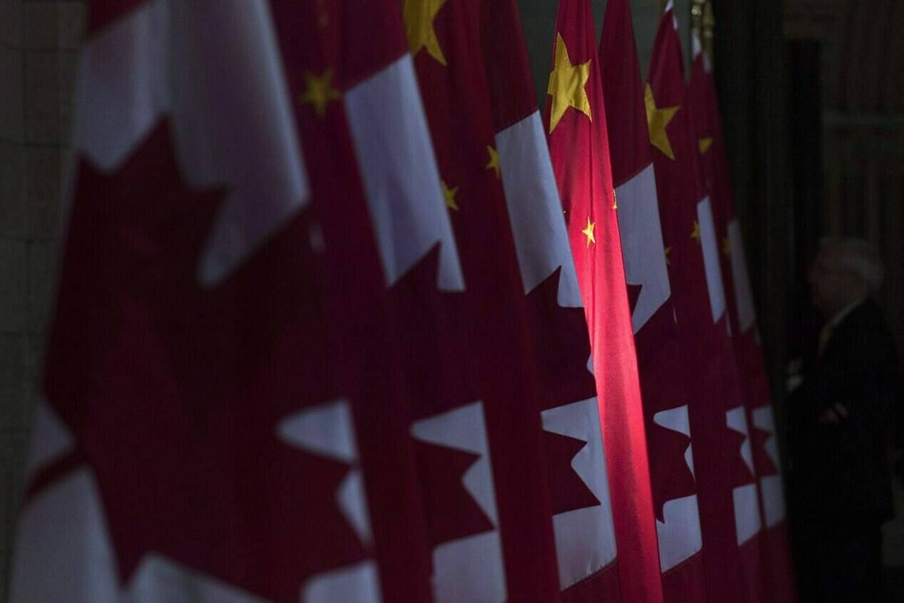A Chinese flag, flanked by Canadian flags, is illuminated by sunshine in the Hall of Honour on Parliament Hill in Ottawa, on Sept. 22, 2016. THE CANADIAN PRESS/Adrian Wyld