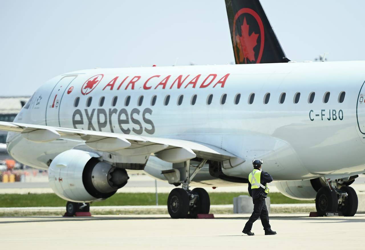 Airline ground crew walks past grounded Air Canada planes as they sit on the tarmac at Pearson International Airport In Toronto on Tuesday, April 27, 2021. THE CANADIAN PRESS/Nathan Denette