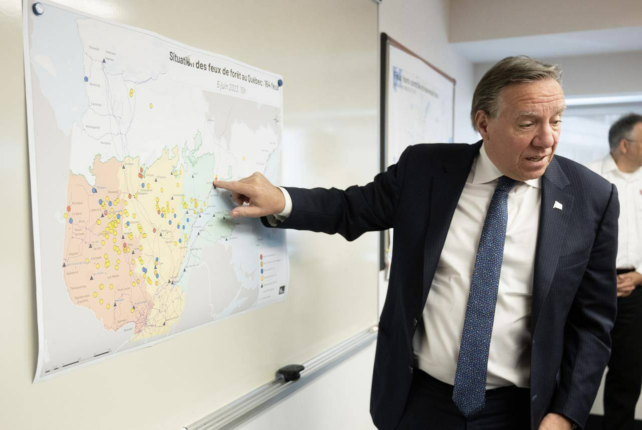 Quebec Premier Francois Legault checks the map where forest fires are raging as he visits the crisis operation centre, in Quebec City, Monday, June 5, 2023. Legault is visiting the community of Sept-Iles, meeting civil security officials and forest firefighter teams. THE CANADIAN PRESS/Jacques Boissinot