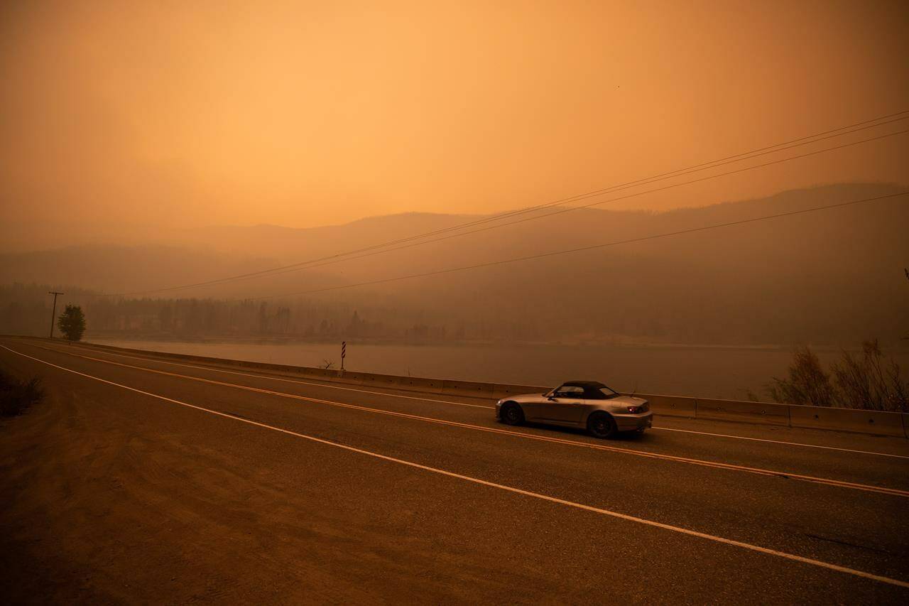 Thick smoke from the White Rock Lake wildfire fills the air and nearly blocks out the sun just after 3 p.m. as a motorist travels on Highway 97 in Monte Lake, east of Kamloops, B.C., Saturday, Aug. 14, 2021. A key highway that connects Yukon and northern British Columbia to southern parts of the province is now threatened by the huge Donnie Creek wildfire as the blaze chews through woodlands south of Fort Nelson. THE CANADIAN PRESS/Darryl Dyck