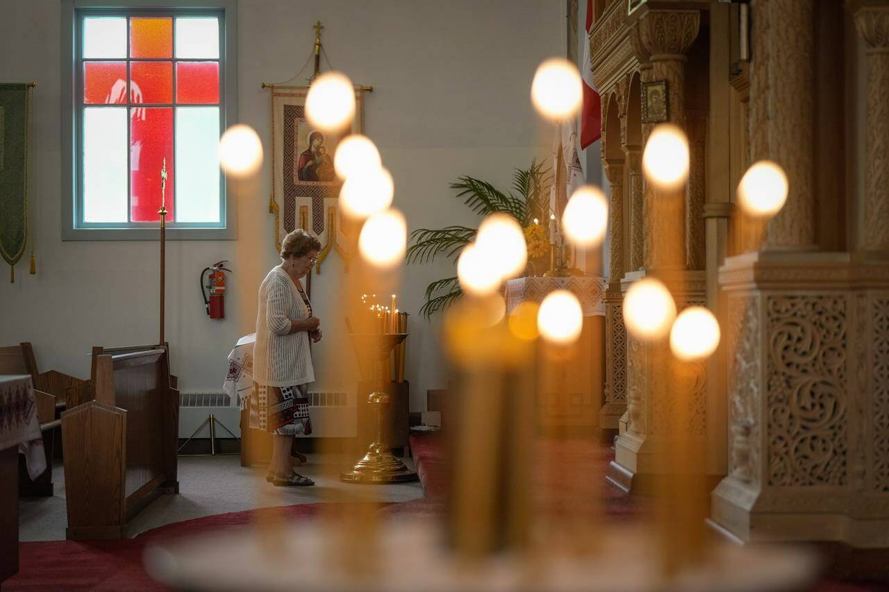 A woman pauses after lighting a candle before Sunday service at St. George’s Ukrainian Orthodox Church, in Dauphin, Man., on Sunday, June 18, 2023. Residents of Dauphin sought solace at church services as they mourn 15 community members who died in a highway crash that also left 10 gravely injured. THE CANADIAN PRESS/Darryl Dyck