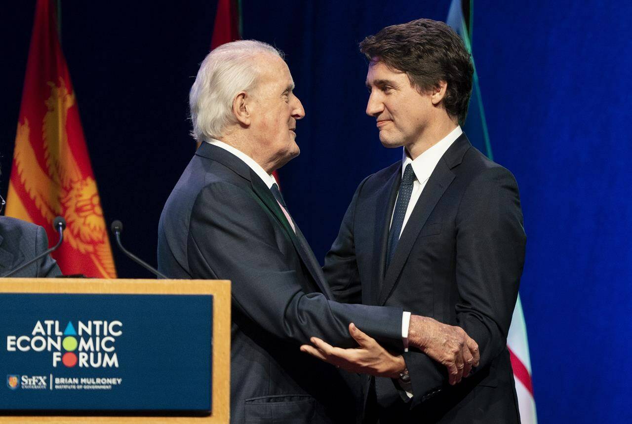 Prime Minister Justin Trudeau, right, and former prime minister Brian Mulroney share a moment on stage during the Atlantic Economic Forum at St. Francis Xavier University, in Antigonish, N.S., on Monday, June 19, 2023. THE CANADIAN PRESS/Darren Calabrese