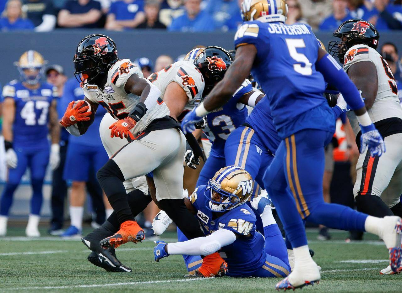 B.C. Lions’ Taquan Mizzell (25) runs for the first down against Winnipeg Blue Bombers’ Alden Darby (2) during first half CFL action in Winnipeg Thursday, June 22, 2023. THE CANADIAN PRESS/John Woods