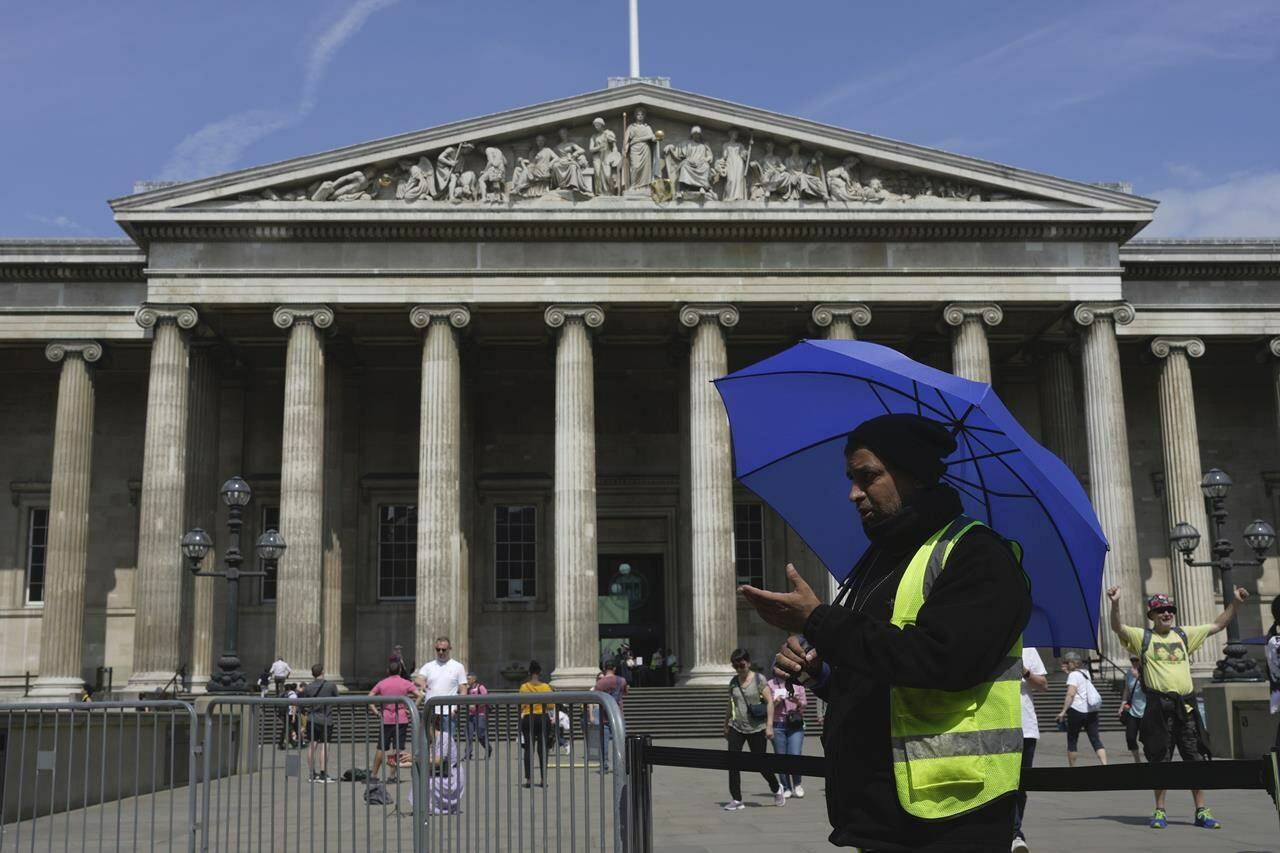 A worker holding an umbrella guides the tourists at British Museum during a hot weather day in Central London, Monday, June 12, 2023. The British Museum says it has removed a Canadian translator’s work from its exhibition after using the translations without permission, attribution or compensation. THE CANADIAN PRESS/AP-Kin Cheung