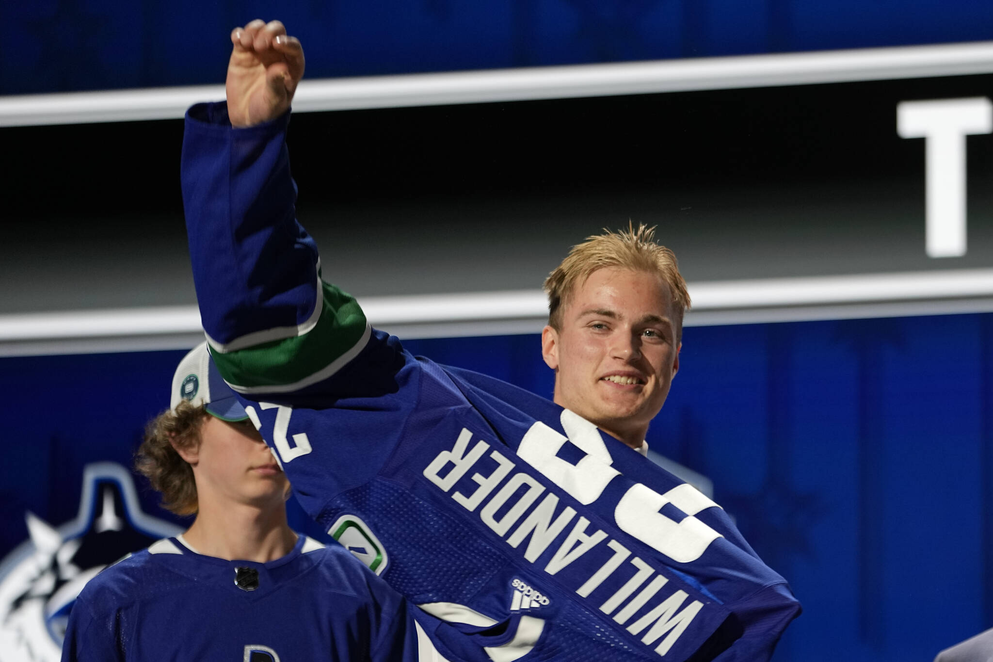 Tom Willander puts on a Vancouver Canucks jersey after being picked by the team during the first round of the NHL hockey draft Wednesday, June 28, 2023, in Nashville, Tenn. (AP Photo/George Walker IV)