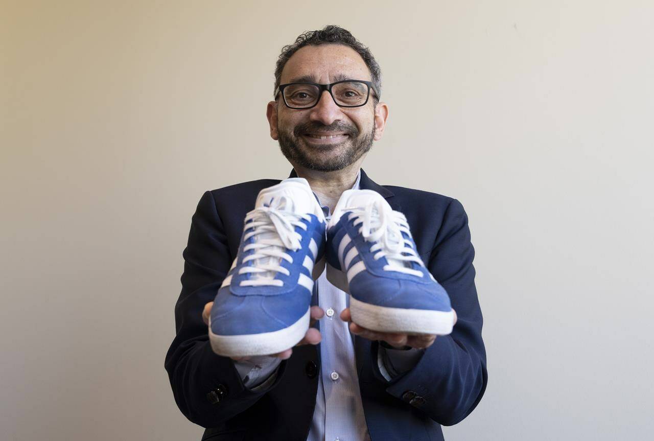 Transport Minister Omar Alghabra holds up a pair of his Adidas shoes as he poses for a photo in Ottawa on Thursday, June 22, 2023. THE CANADIAN PRESS/Adrian Wyld