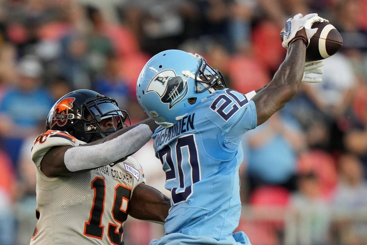 Toronto Argonauts defensive back Tarvarus McFadden (20) makes an interception over BC Lions wide receiver Dominique Rhymes (19) during first half CFL action in Toronto on Monday, July 3, 2023. THE CANADIAN PRESS/Frank Gunn