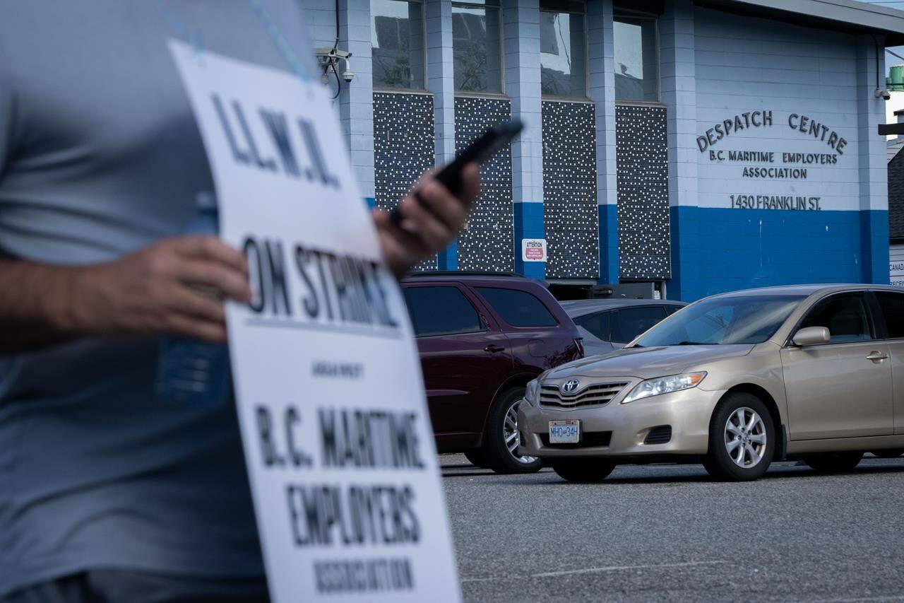 An International Longshore and Warehouse Union worker pickets outside of the BC Maritime Employers Association Dispatch Centre after a 72-hour strike notice and no agreement made on the bargaining table in Vancouver, on Saturday, July 1, 2023. THE CANADIAN PRESS/Ethan Cairns