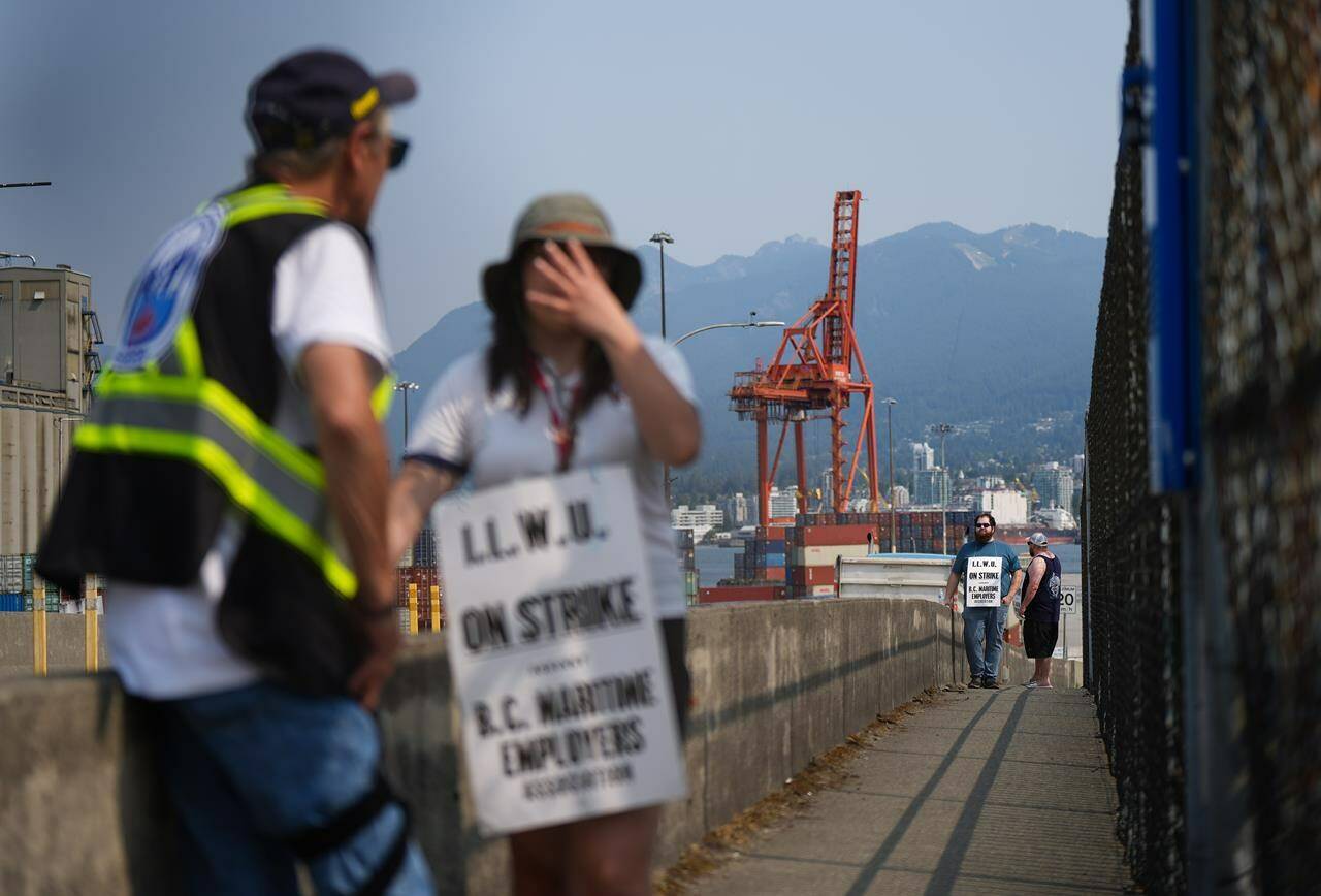 Striking International Longshore and Warehouse Union Canada workers picket at a port entrance in Vancouver, B.C., Tuesday, July 4, 2023. The strike at more than 30 British Columbia ports entered its fourth day on Tuesday after 7,400 port workers walked off the job on the weekend. THE CANADIAN PRESS/Darryl Dyck