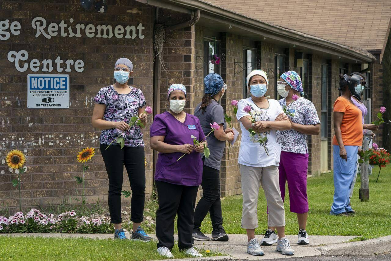 Workers hold flowers given to them as they watch as 150 nursing union members show support at Orchard Villa Long-Term Care in Pickering, Ont. on Monday, June 1, 2020. The National Institute on Aging found provincial long-term care standards vary drastically across the country and in some cases fall far short of the new national standards released earlier this year. THE CANADIAN PRESS/Frank Gunn