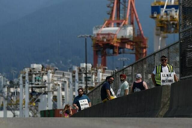 Striking International Longshore and Warehouse Union Canada workers picket at a port entrance in Vancouver, B.C., Tuesday, July 4, 2023. Talks between maritime employers and the union representing British Columbia port workers remain deadlocked over maintenance issues as a strike by the workers enters its fifth day. THE CANADIAN PRESS/Darryl Dyck