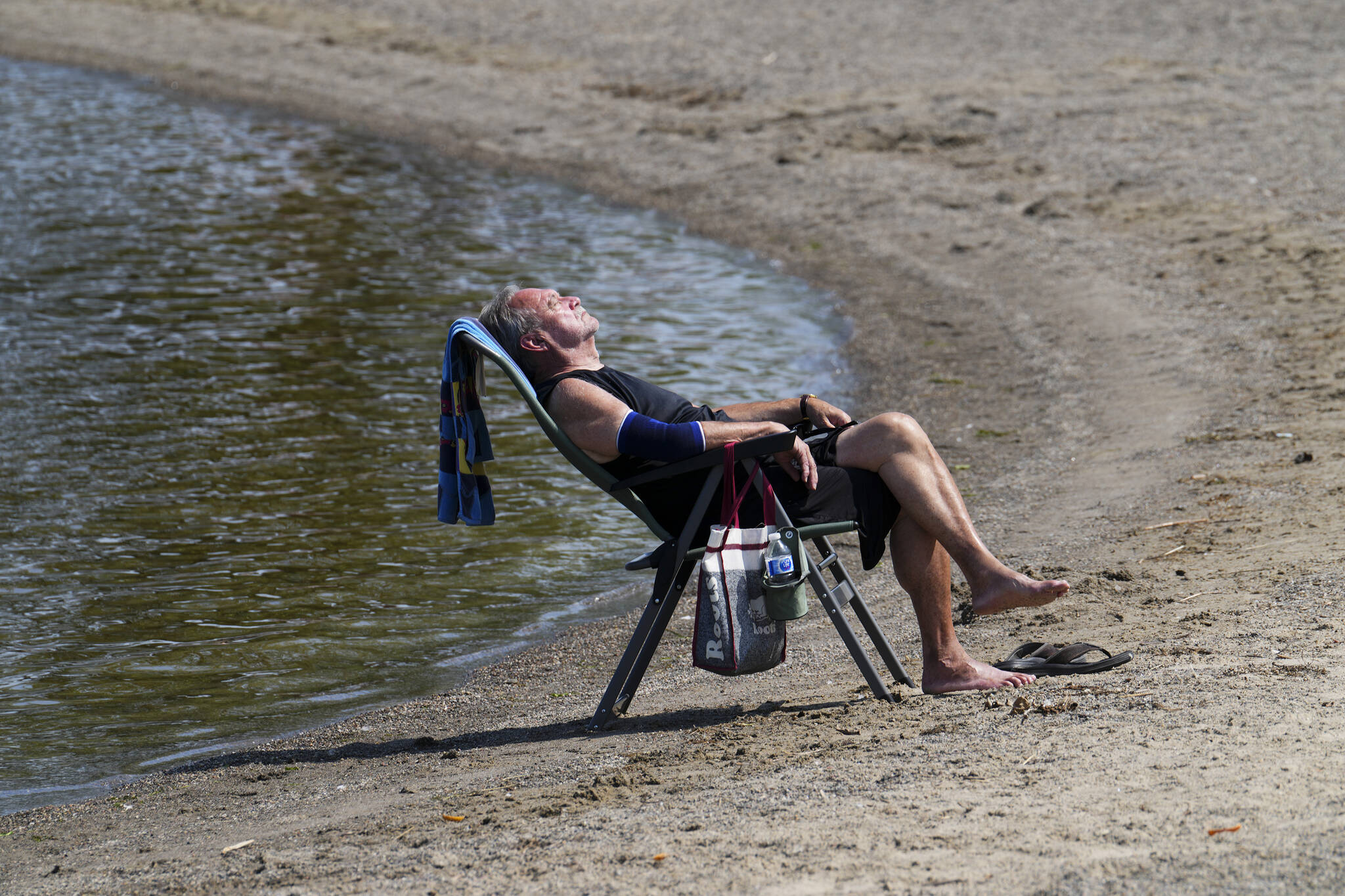 Duane relaxes on the banks of the Ottawa River in Ottawa on Tuesday, July 4, 2023. Several parts of Canada continue to swelter under intense heat, prompting extreme weather warnings. THE CANADIAN PRESS/Sean Kilpatrick