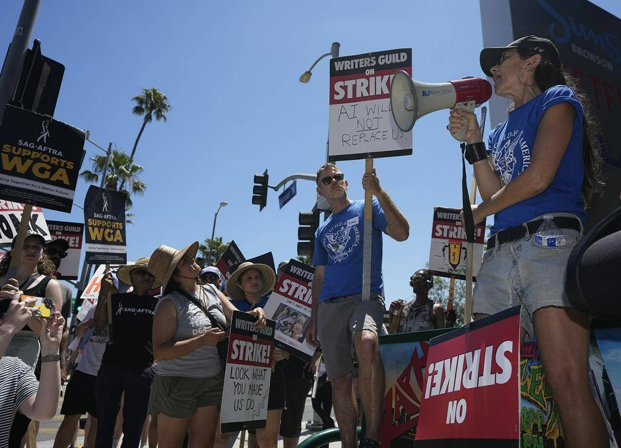 Justine Bateman, right, speaks outside Netflix during a Writers Guild rally as a strike by The Screen Actors Guild-American Federation of Television and Radio Artists is announced on Thursday, July 13, 2023, in Los Angeles. This marks the first time since 1960 that actors and writers will picket film and television productions at the same time. (AP Photo/Mark J. Terrill)