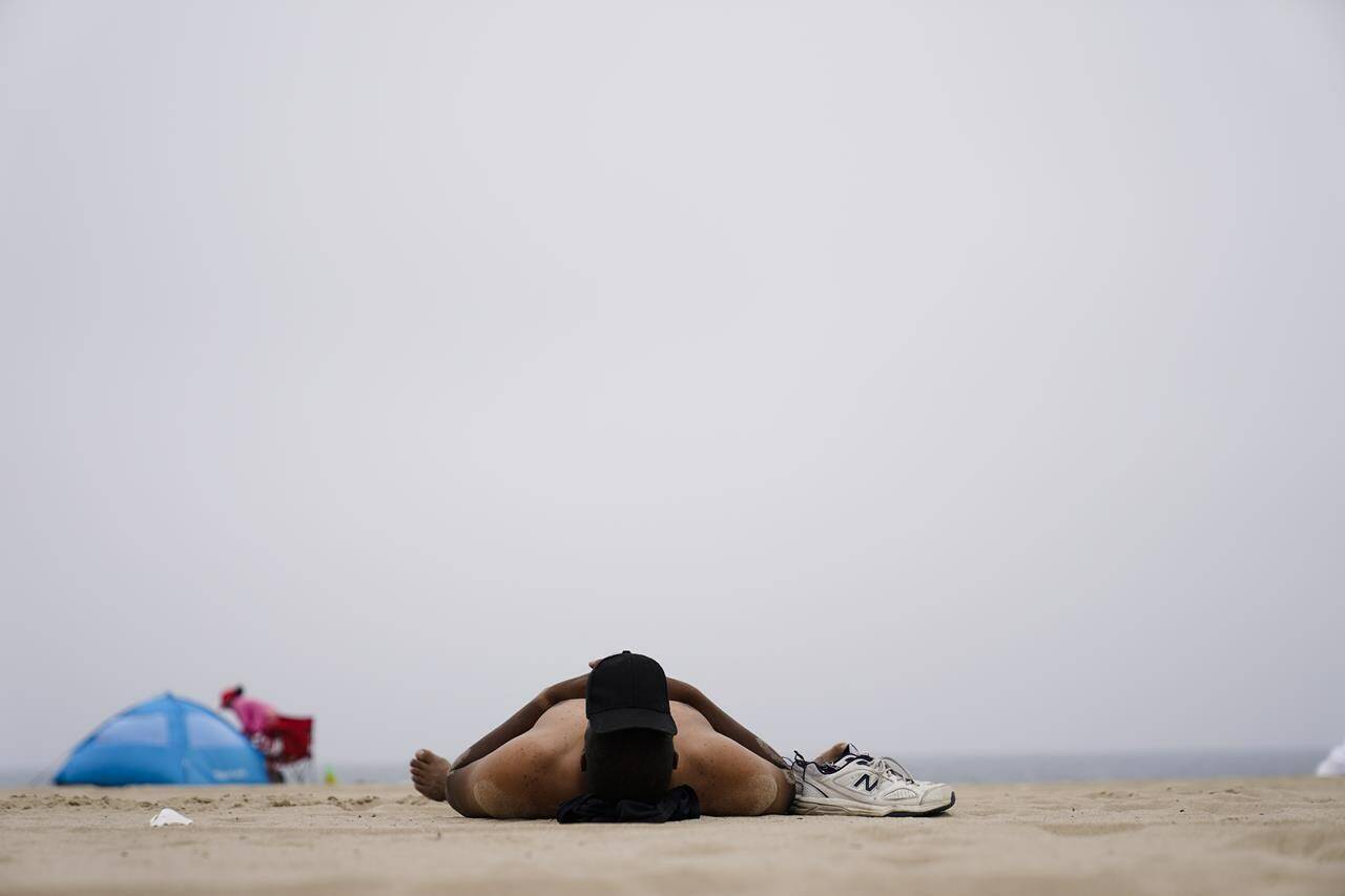 A man lies on the beach, Tuesday, July 11, 2023, in Los Angeles. Los Angeles is expecting high temperatures between 100 to 110 degrees Fahrenheit later this week according to the National Weather Service. (AP Photo/Ryan Sun)