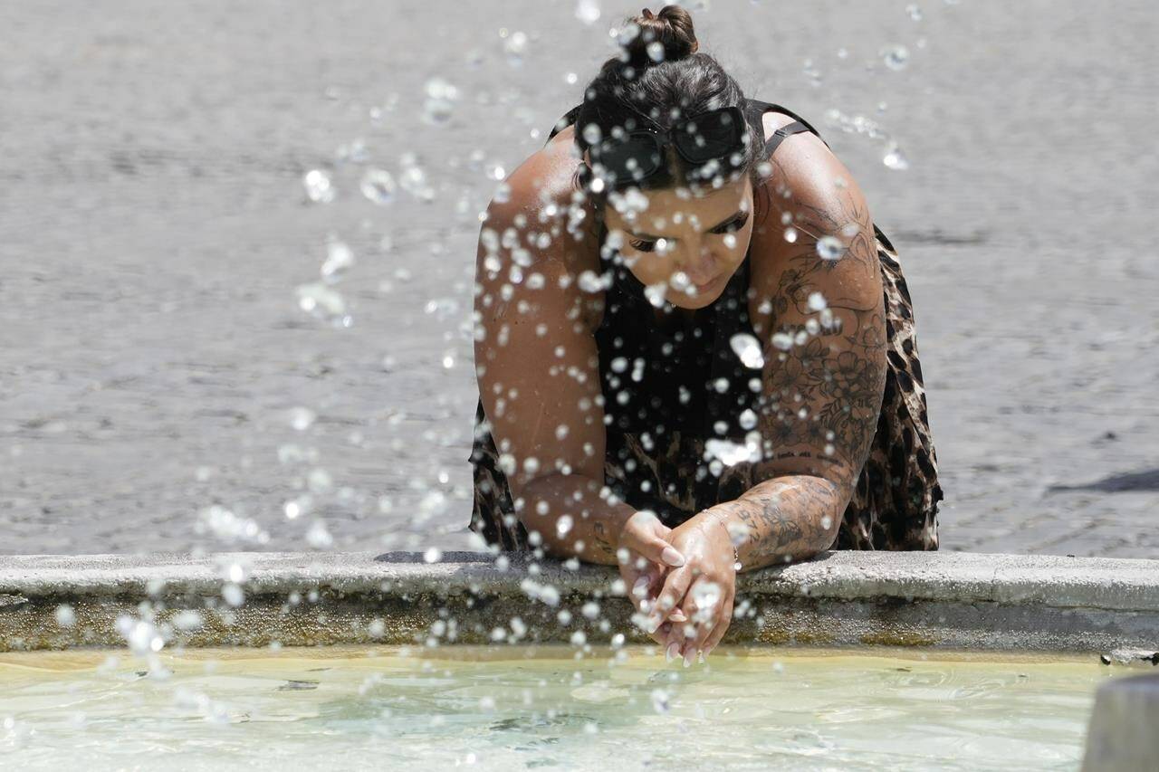 A woman leans by the Lions fountain in Rome, Tuesday, July 18, 2023. Tourist flock to the eternal city while scorching temperatures grip central Italy with Rome at the top of the red alert list as one of the hottest cities in the country. (AP Photo/Gregorio Borgia)