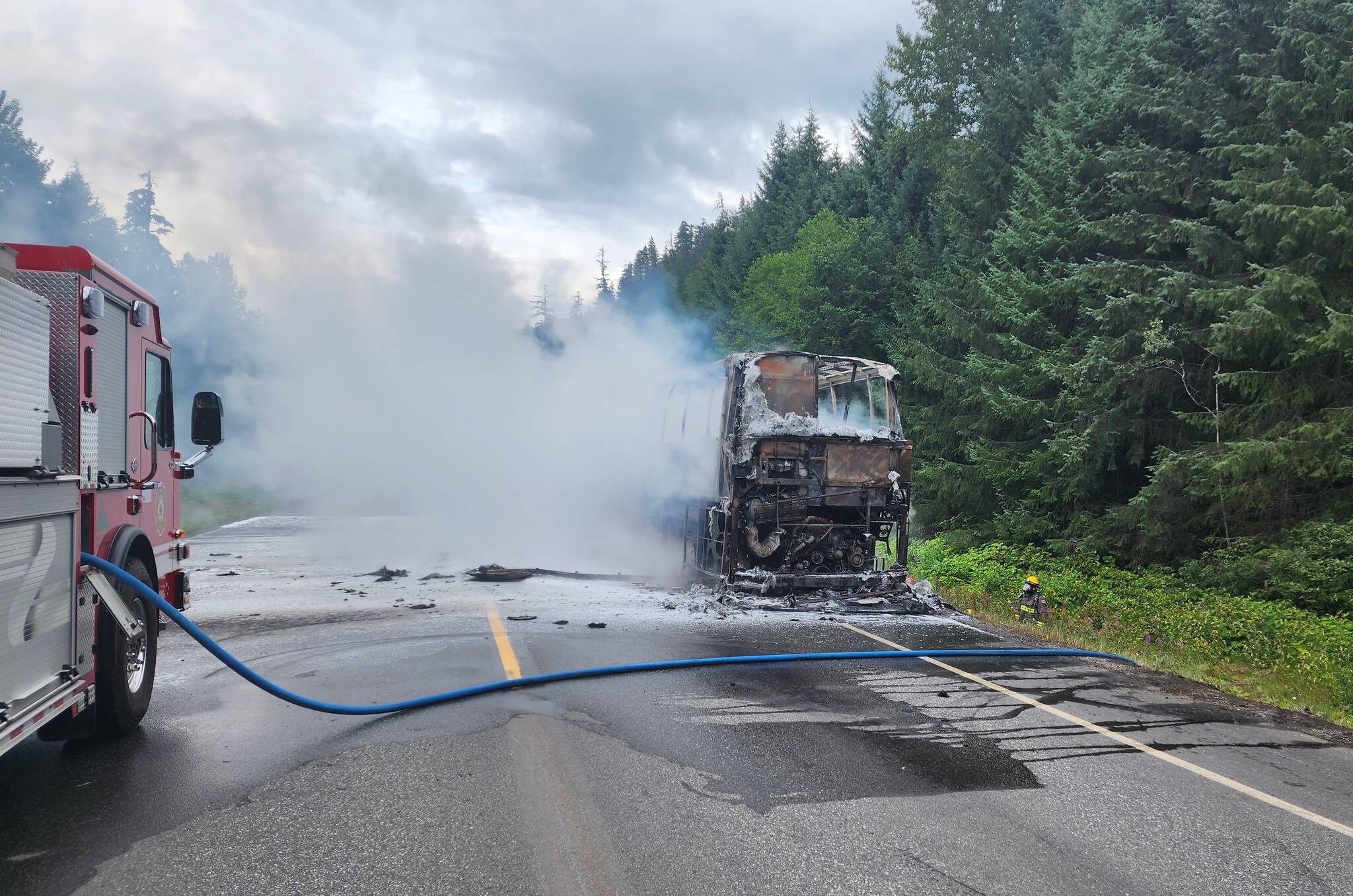 The charred tour bus smoulders on Hwy 16 near Skeena West after a midday fire on July 16 that left 37 international tourists stranded. There were no injuries and the Thornhill Fire Department was quick to respond, helping passengers get back on the road within seven hours. (Thornhill Fire Department photo)