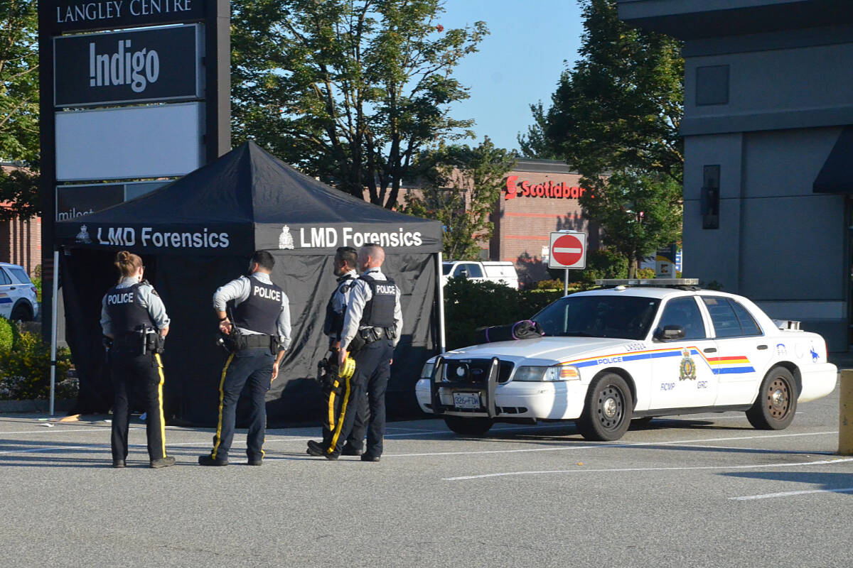 RCMP next to a Forensics tent and a Langley RCMP crusier that appears to have damage to a passenger side window, in the parking lot near the corner of the Langley Bypass and 200th Street, Monday morning at 7:20 a.m. Nearby was a white sedan matching the description of the suspect vehicle in multiple shooting incidents in Langley. (Matthew Claxton/Langley Advance Times)