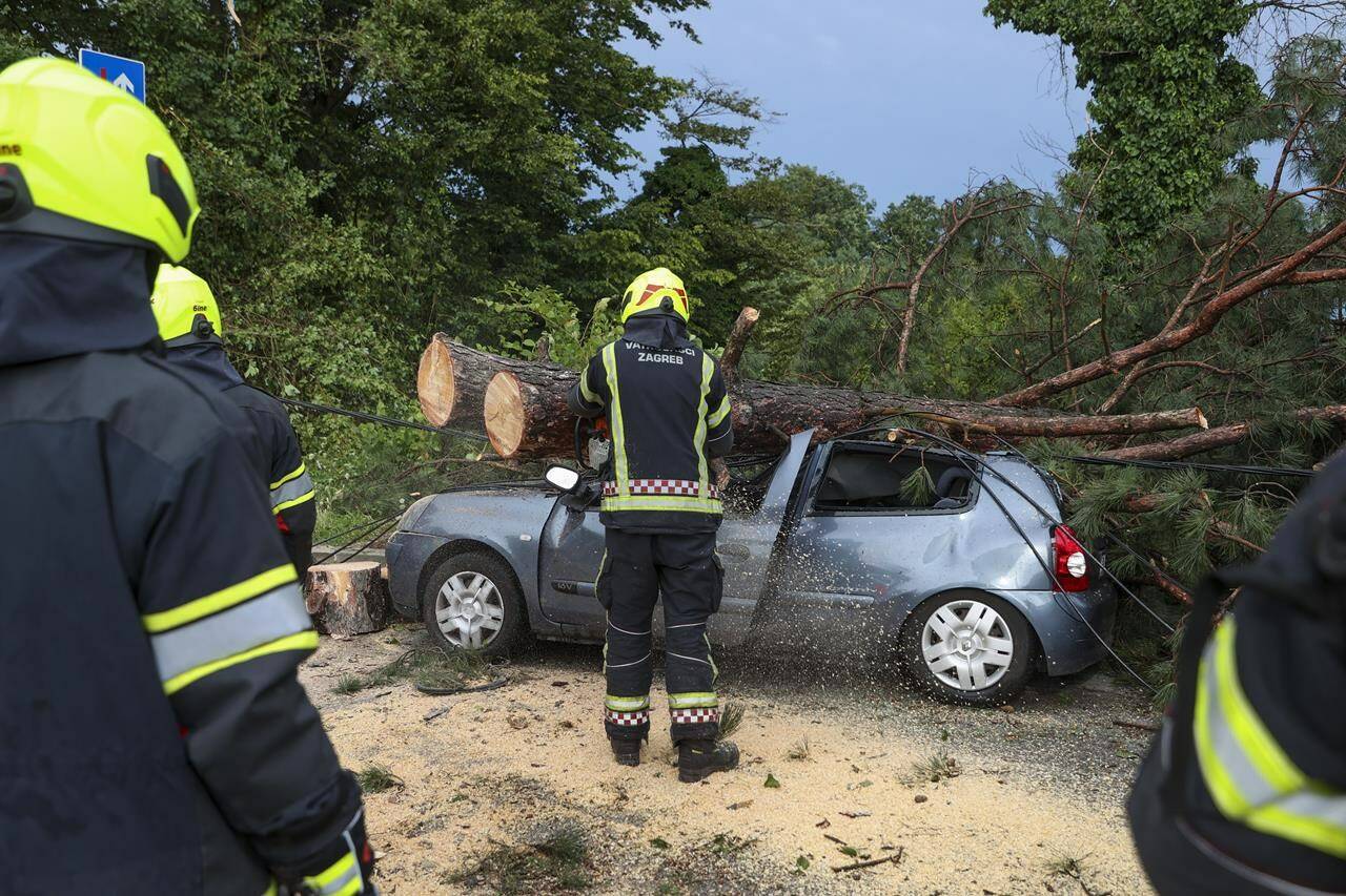 Firefighters remove fallen tree branches from damaged parked car after a powerful storm, in Zagreb, Croatia, Wednesday, July 19, 2023. A powerful storm with strong winds and heavy rain hit Croatia and Slovenia on Wednesday, killing at least three people and injuring several others. (AP Photo)