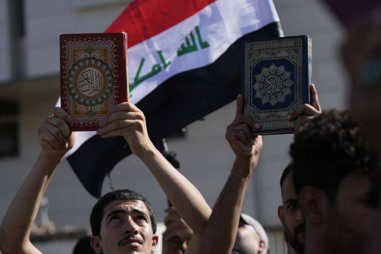 FILE - Supporters of the Shiite cleric Muqtada al-Sadr raise the Quran, the Muslims’ holy book, during a demonstration in front of the Swedish Embassy in Baghdad, on June 30, 2023, in response to the burning of Quran in Sweden. Protesters angered by the burning of a copy of the Quran stormed the Swedish Embassy in Baghdad early Thursday, July 20, 2023, online videos purported to show. (AP Photo/Hadi Mizban, File)