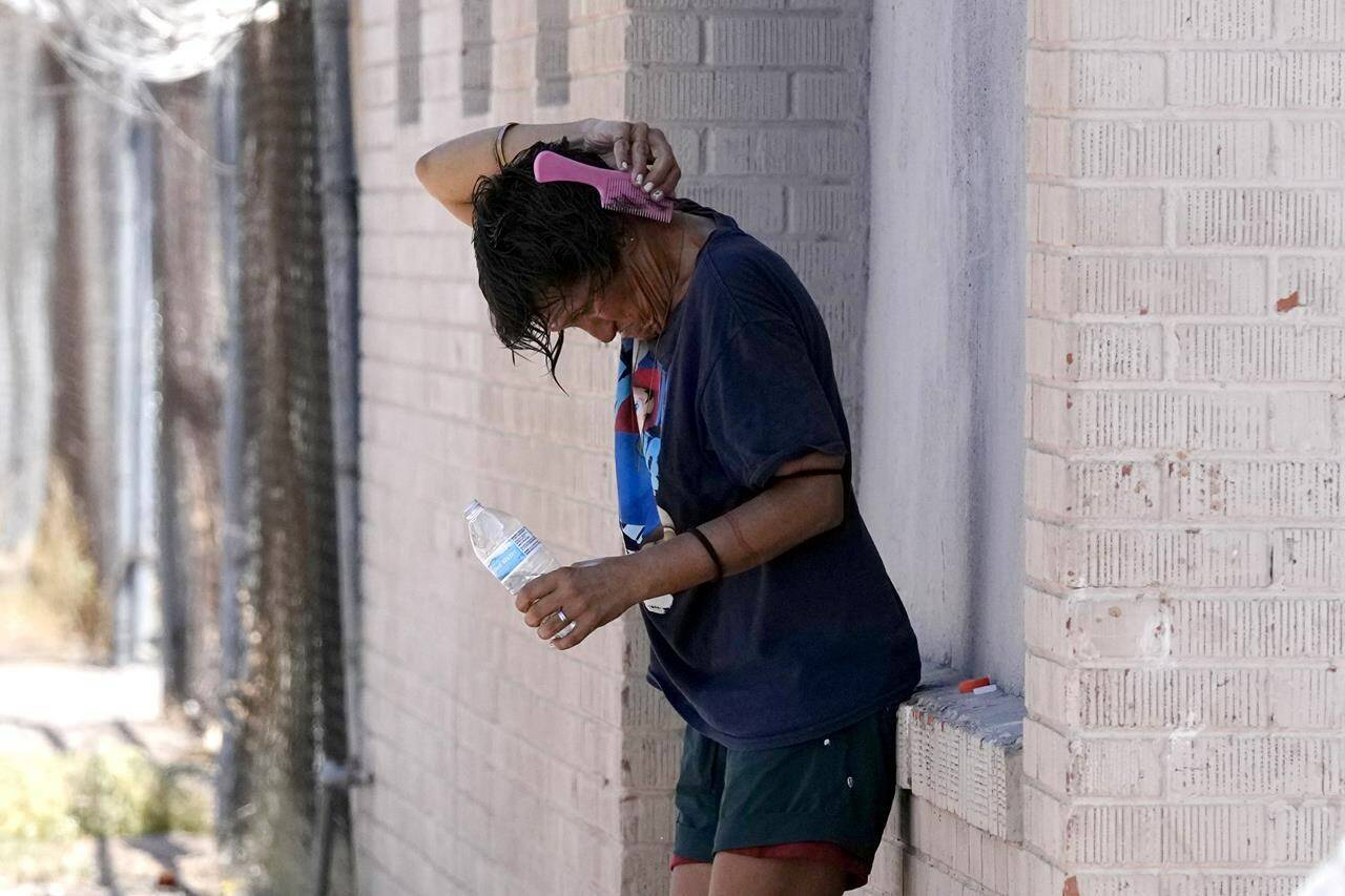 A person tries to cool off in the shade as temperatures are expected to hit 116-degrees Fahrenheit, Tuesday, July 18, 2023, in Phoenix. The extreme heat scorching Phoenix set a record Tuesday, the 19th consecutive day temperatures hit at least 110 degrees Fahrenheit. (AP Photo/Ross D. Franklin)