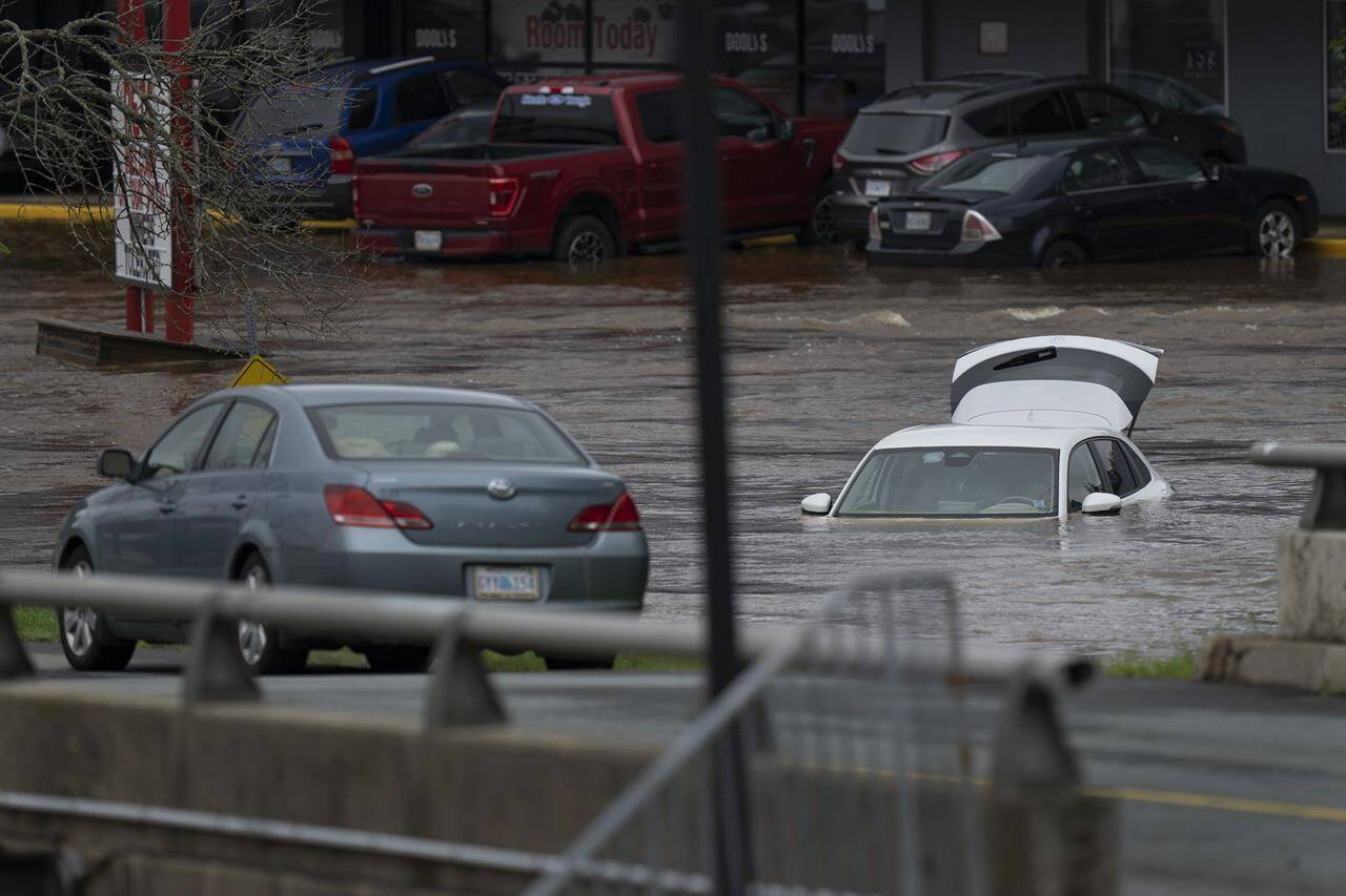 Abandoned cars in a mall parking lot are seen in floodwater following a major rain event in Halifax on Saturday, July 22, 2023. Nova Scotia RCMP say the search continues for four people, including two children, after intense thunderstorms dumped record amounts of rain across the province. THE CANADIAN PRESS/Darren Calabrese