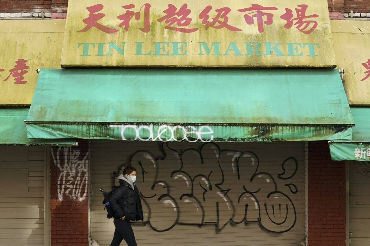 A woman walks in Chinatown in Vancouver, Friday, February 5, 2021. The provincial government has announced up to $10.5 million for small businesses to apply for grants for repairs for vandalism or prevention. The announcement was in Chinatown on Wednesday (July 26, 2023) which has been hard hit by vandalism in recent years. THE CANADIAN PRESS/Jonathan Hayward