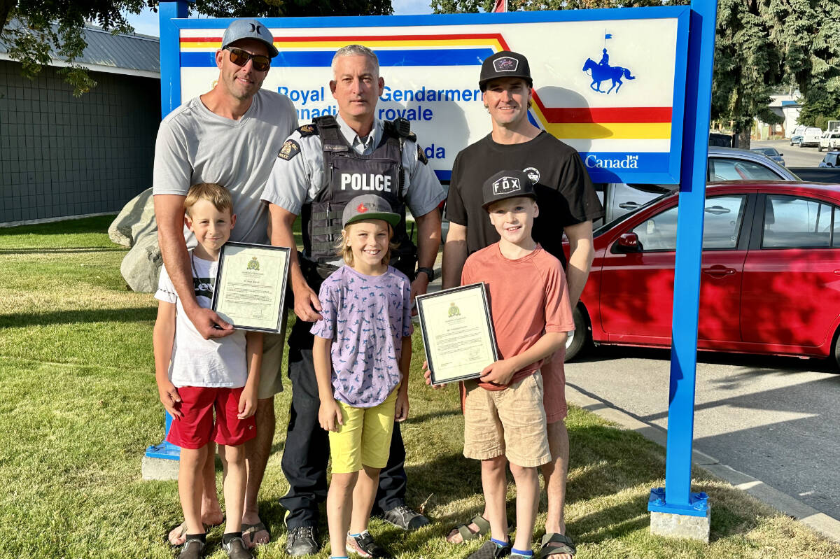 Kimberley RCMP detachment commander Sgt. Steven Woodcox (centre) presents Jason Sherratt (left) and Chris Pearson (right), and their boys Nixen Sherratt (front left) and Cooper and Cole Pearson with certificates of appreciation for saving the life of a three-year-old girl who nearly drowned in Wasa Lake. Paul Rodgers photo.