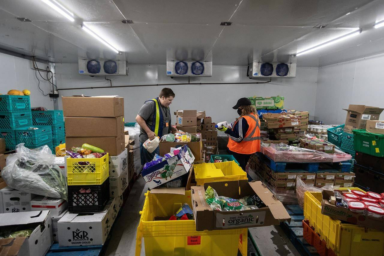 Workers gather food for a homeless mission while at the Edmonton Food Bank, in Edmonton on Friday July 21, 2023. THE CANADIAN PRESS/Jason Franson.