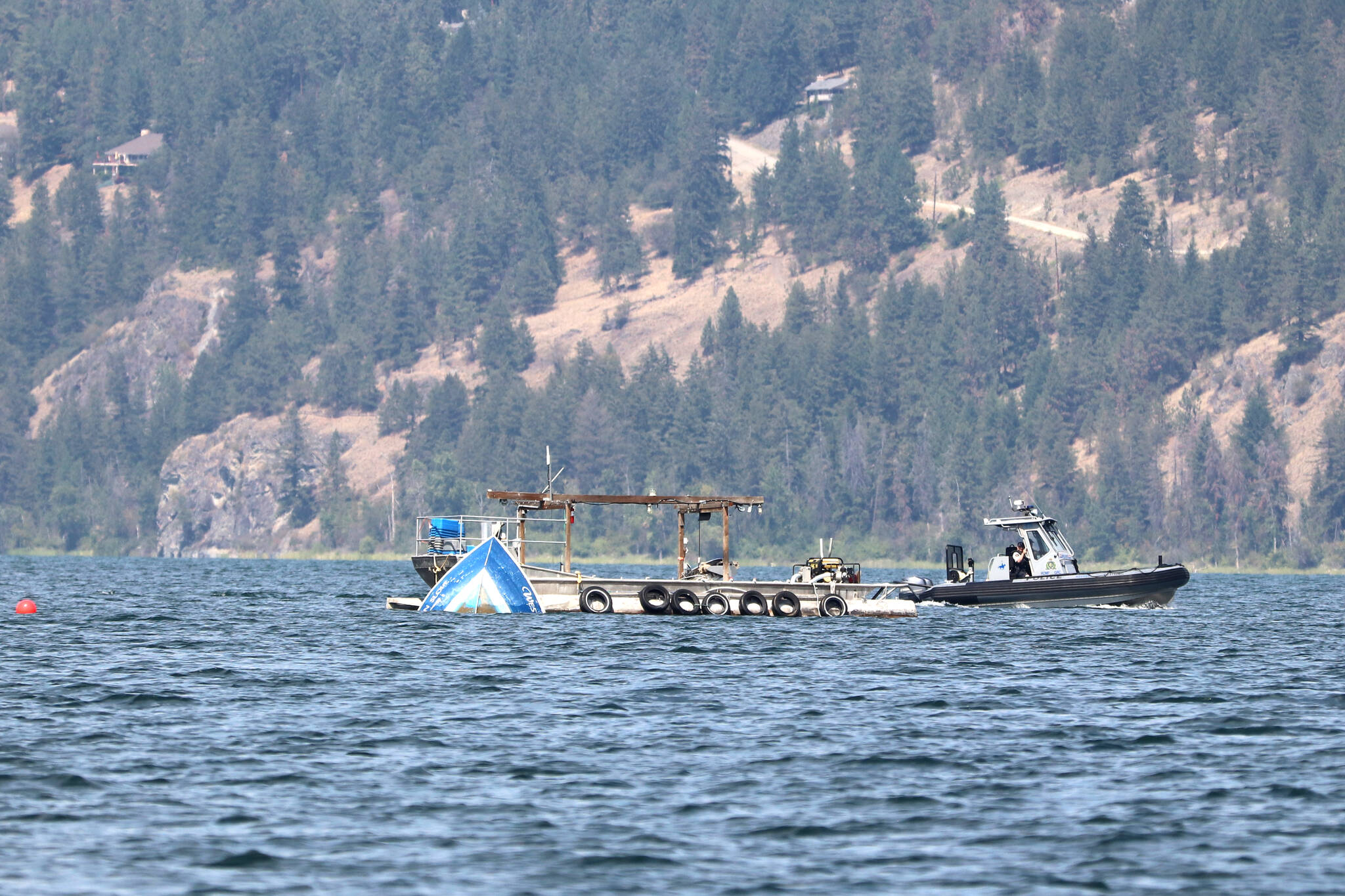 An RCMP boat circles the wreckage of a commercial fishing boat in Okanagan Lake, where the captain has not resurfaced or been found since overturning Monday, July 24. (Jennifer Smith - Morning Star)