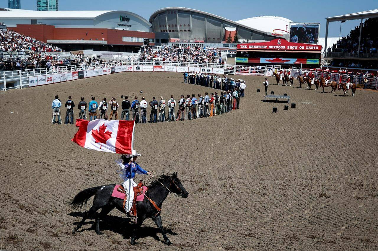 Competitors gather for the national anthem before the rodeo at the Calgary Stampede on Saturday, July 8, 2023. One of the plaintiffs in a class-action lawsuit against the Stampede says he agrees with a member of Parliament who wants the federal government to temporarily withdraw funding for the organization. THE CANADIAN PRESS/Jeff McIntosh
