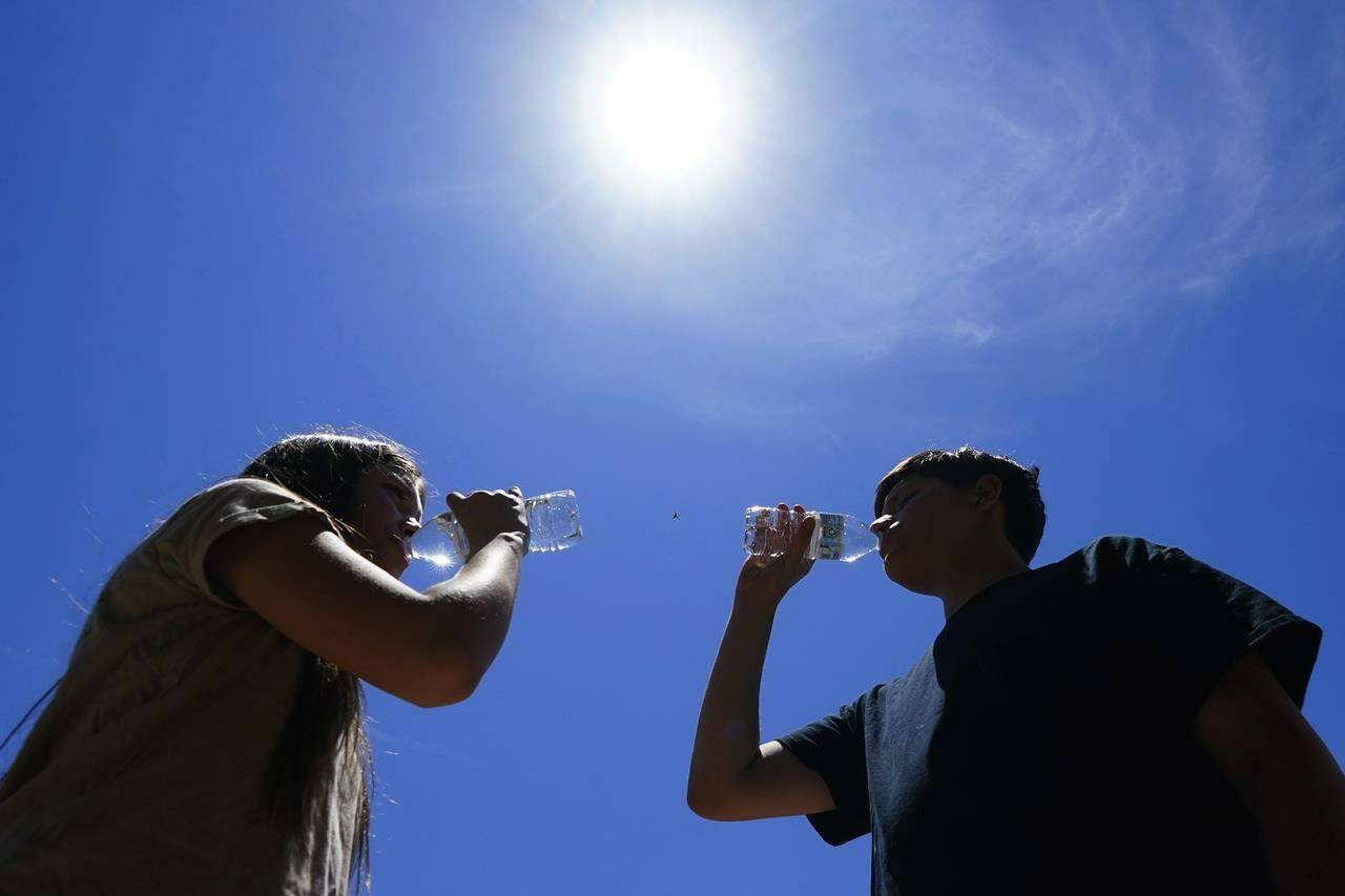 Tony Berastegui Jr., 15, right, and his sister Giselle Berastegui, 12, drink water as temperatures are expected to hit 46 C on Monday, July 17, 2023, in Phoenix. Much of the populous U.S. northeast is facing temperatures Friday and Saturday that will feel like 40 C or higher. THE CANADIAN PRESS/AP/Ross D. Franklin