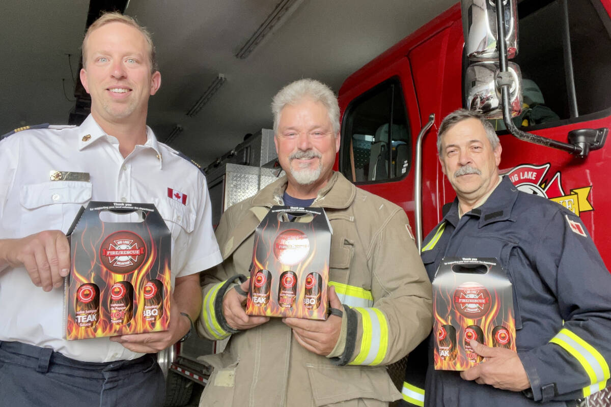 Big Lake Volunteer Fire Rescue fire chief Joel Bruneski, from left, deputy chief Mark Wilkie, and communications officer Ken Waters hold up some samples of the sauces Wilkie developed to help raise funds for the BLVFR. The department is hosting a barbecue fundraiser event at the Big Lake Fire Hall on July 30, 2023 from 1-3 p.m. to provide samples, engage with the community and sell the sauces as a fundraiser for their department. (Photo submitted)