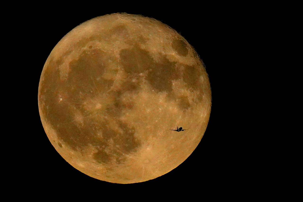 FILE - A commercial airliner flies Northwest across Lake Michigan in front of the “Full Buck” supermoon, the first of four supermoons in 2023, July 3, 2023, in Chicago. The cosmos is offering up a double feature in August: a pair of supermoons. Catch the first show Tuesday night, Aug. 2, as the full moon rises in the southeast. (AP Photo/Charles Rex Arbogast, File)