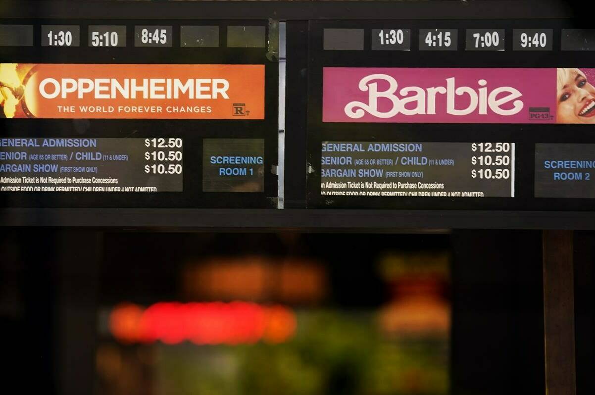 Showtimes for the films “Oppenheimer” and “Barbie” are pictured behind the box office window at the Los Feliz Theatre, Friday, July 28, 2023, in Los Angeles. (AP Photo/Chris Pizzello)