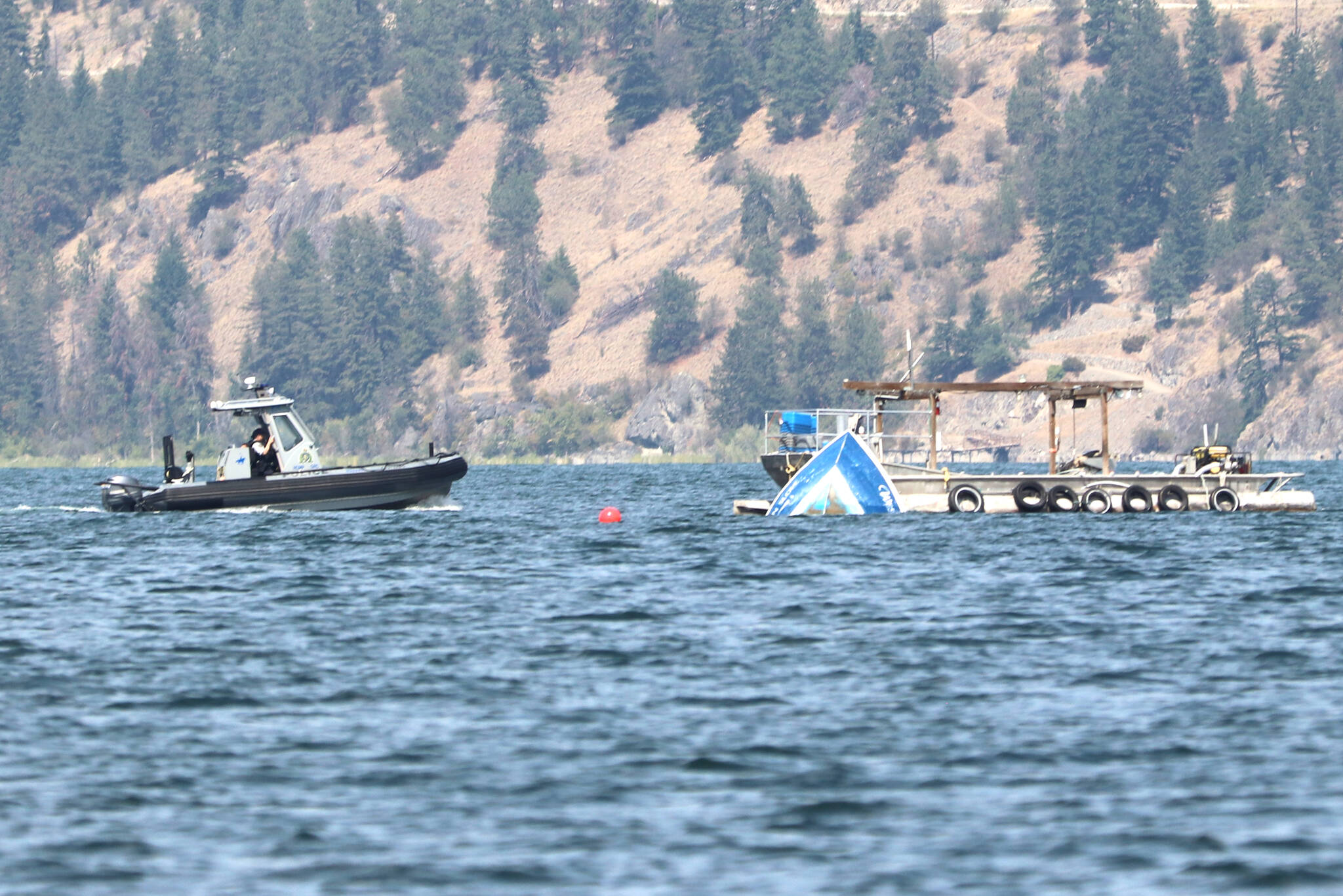 An RCMP boat circles the wreckage of a commercial fishing boat in Okanagan Lake, where the captain has not resurfaced or been found since overturning Monday, July 24. (Jennifer Smith - Morning Star)