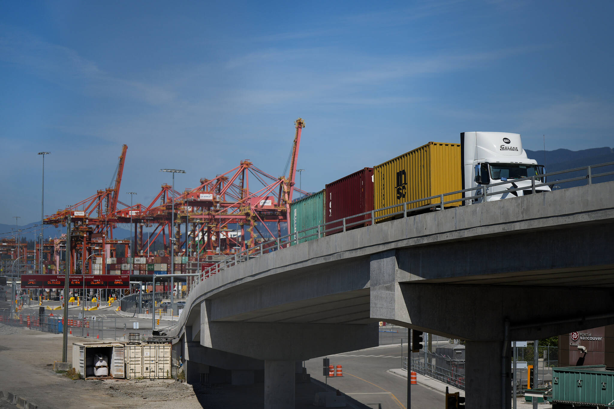 A transport truck carries cargo containers from the Centerm Container Terminal at port in Vancouver, on Friday, July 14, 2023. British Columbia port workers are back on the job after a tentative agreement was reached between the employers association and the workers union, ending a 13-day-old strike. THE CANADIAN PRESS/Darryl Dyck