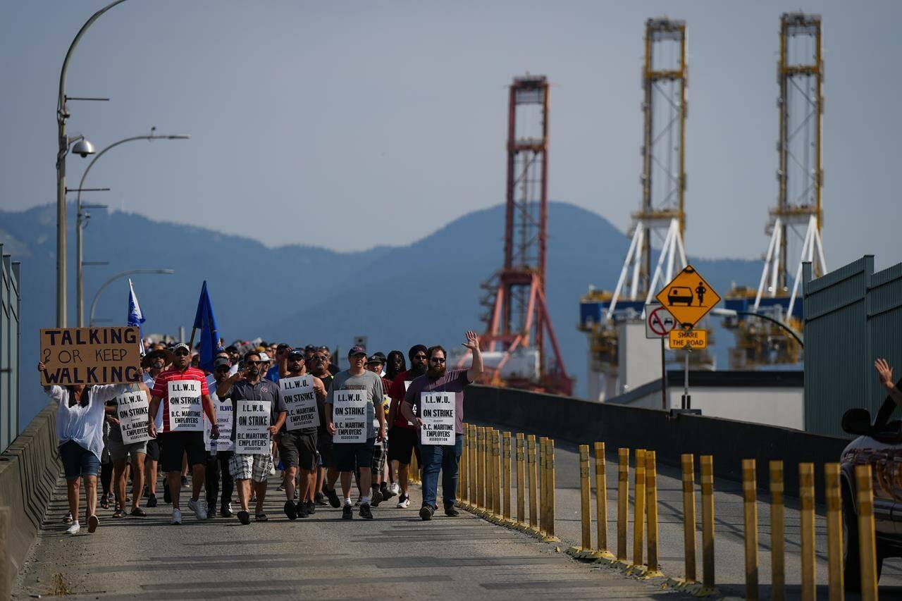 Striking International Longshore and Warehouse Union Canada workers march to a rally as gantry cranes used to load and unload cargo containers from ships sit idle at port in Vancouver on Thursday, July 6, 2023. The recently concluded strike was part of a larger surge of strikes across North America. (THE CANADIAN PRESS/Darryl Dyck)