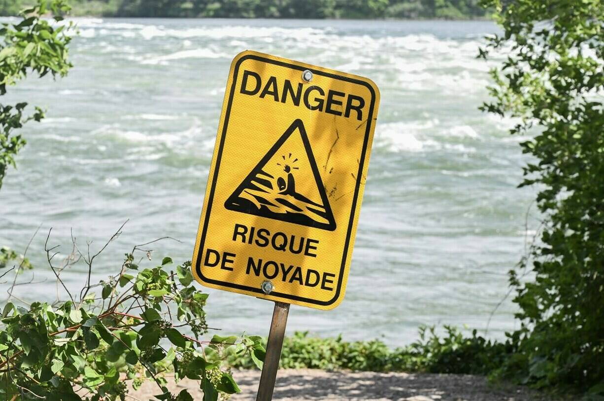 A sign that translates to “risk of drowning,” is shown next to the St. Lawrence River in Montreal on Monday, June 26, 2023. It has been a particularly deadly year on the water in Quebec, which so far accounts for more than a third of all drownings reported in the country. THE CANADIAN PRESS/Graham Hughes
