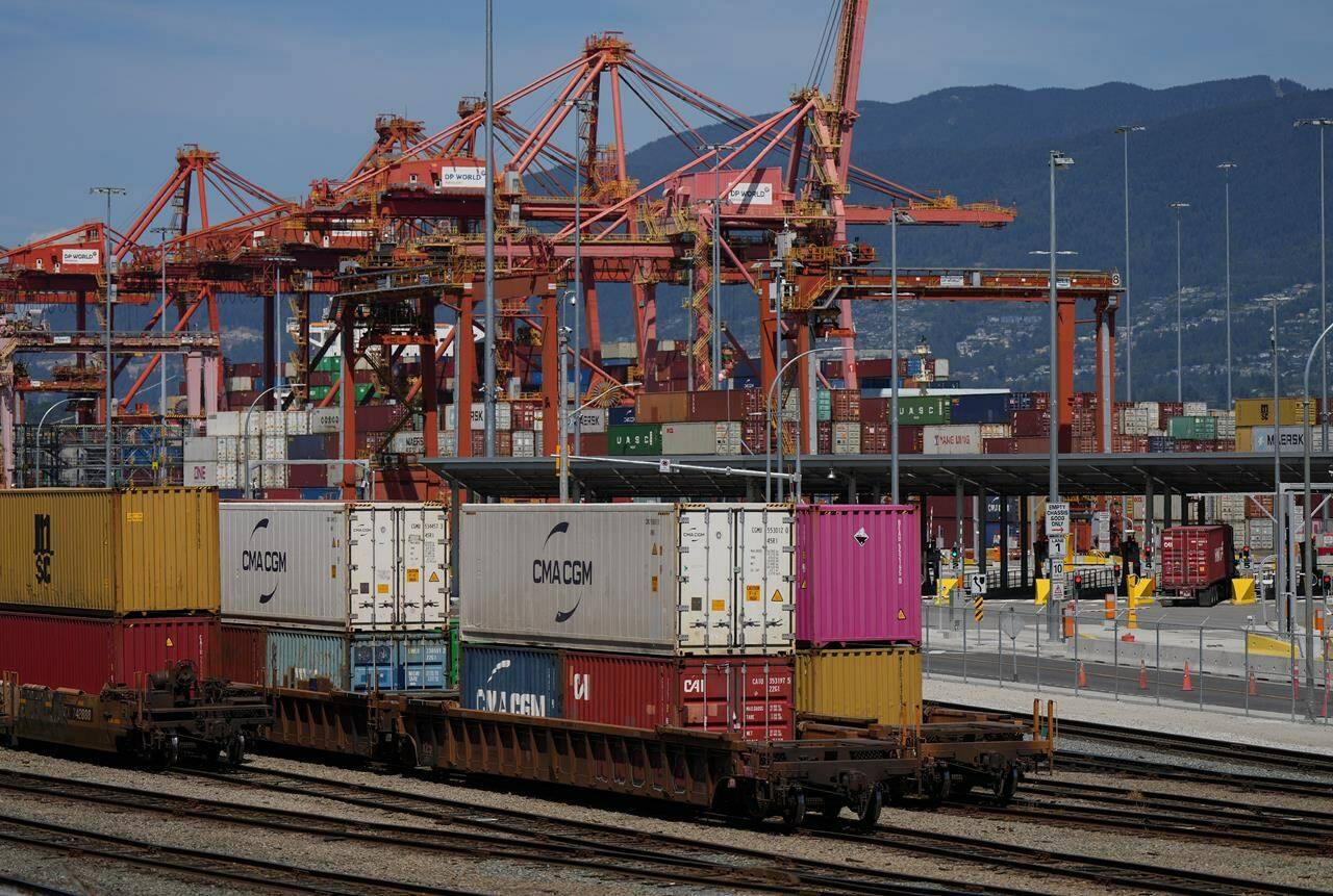 A transport truck carries a cargo container to the Centerm Container Terminal at port in Vancouver on Friday, July 14, 2023. The Canada Industrial Relations Board has released the new terms of the agreement that resolved British Columbia's port dispute, including a commitment by employers to train workers to perform maintenance on new equipment. THE CANADIAN PRESS/Darryl Dyck