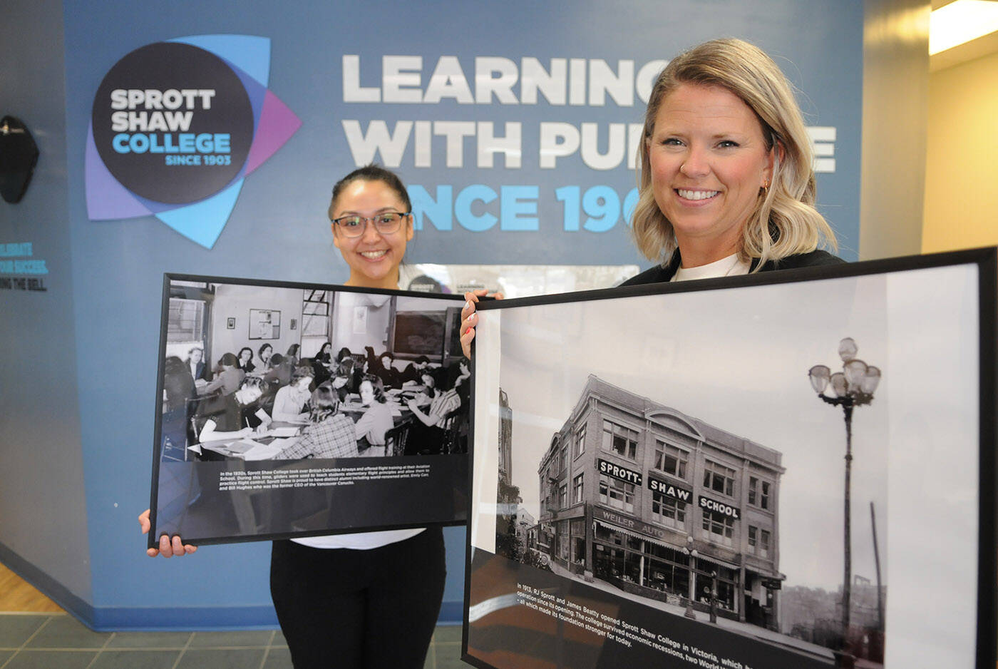 Britni Hannah (right), director of Sprott Shaw College Chilliwack campus, and Marissa Bell, employment services specialist, hold historic images of the school that will be on display at the 120th anniversary celebration on Aug. 17. (Jenna Hauck/ Chilliwack Progress)