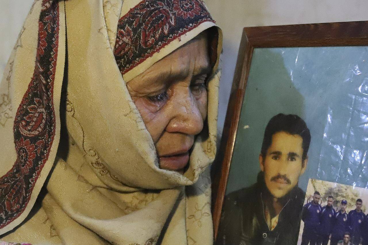 The mother of Mohammed Hassan, a Pakistani porter who died on July 27 during a summit of K2, weeps while she holds a portrait of him at their home in Tasar, a village in the Shigar district in the Gilgit-Baltistan region of northern Pakistan, Saturday, Aug. 12, 2023. An investigation has been launched into the death of a Hassan near the peak of the world’s most treacherous mountain, a Pakistani mountaineer said Saturday, following allegations that dozens of climbers eager to reach the summit had walked past the man after he was gravely injured in a fall. (AP Photo/M.H. Balti)
