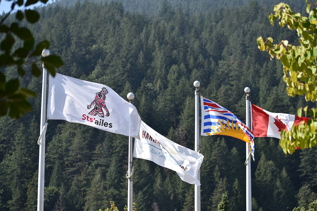 The Sts’ailes First Nation flag flies beside the Harrison Hot Springs, British Columbia and Canadian flags in the village. (Observer File Photo)