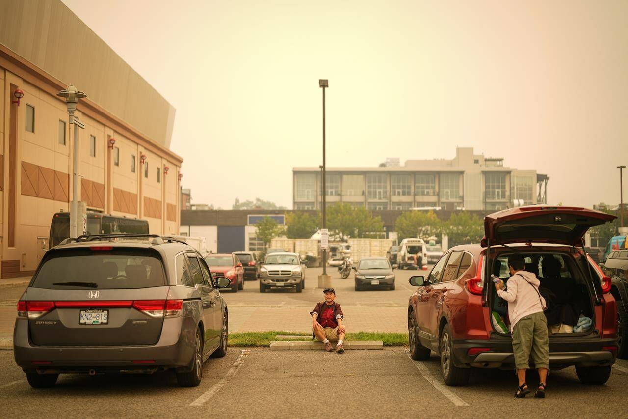 The Central Okanagan is facing weeks without tourism during its peak season after British Columbia’s premier imposed bans on travel to wildfire zones. A man sits in the parking lot outside an evacuation centre for those forced from their homes due to wildfires, in Kelowna, B.C., Saturday, Aug. 19, 2023. THE CANADIAN PRESS/Darryl Dyck