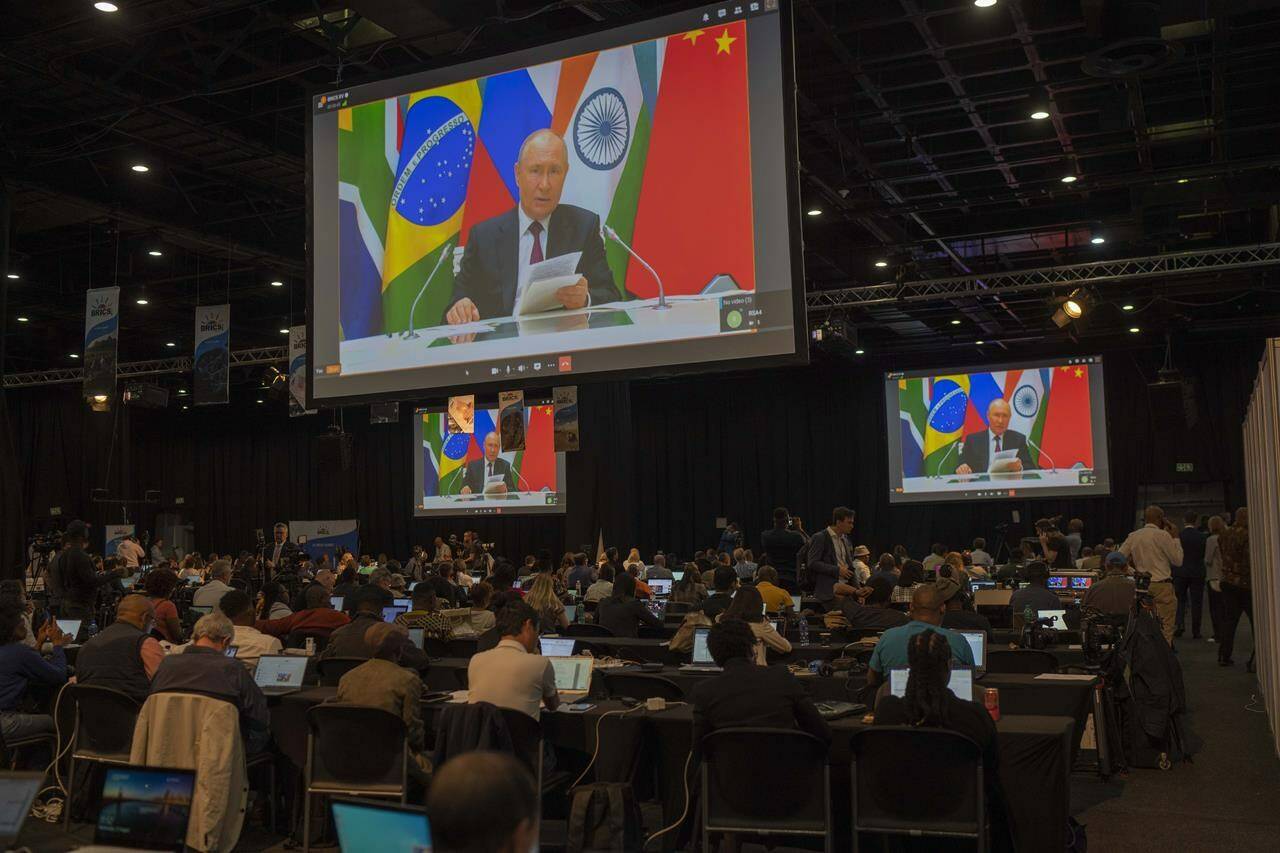 Members of the media watch Russia's President Vladimir Putin address via videolink the 2023 BRICS Summit in Johannesburg, South Africa, Wednesday, Aug. 23, 2023. (AP Photo/Jerome Delay)