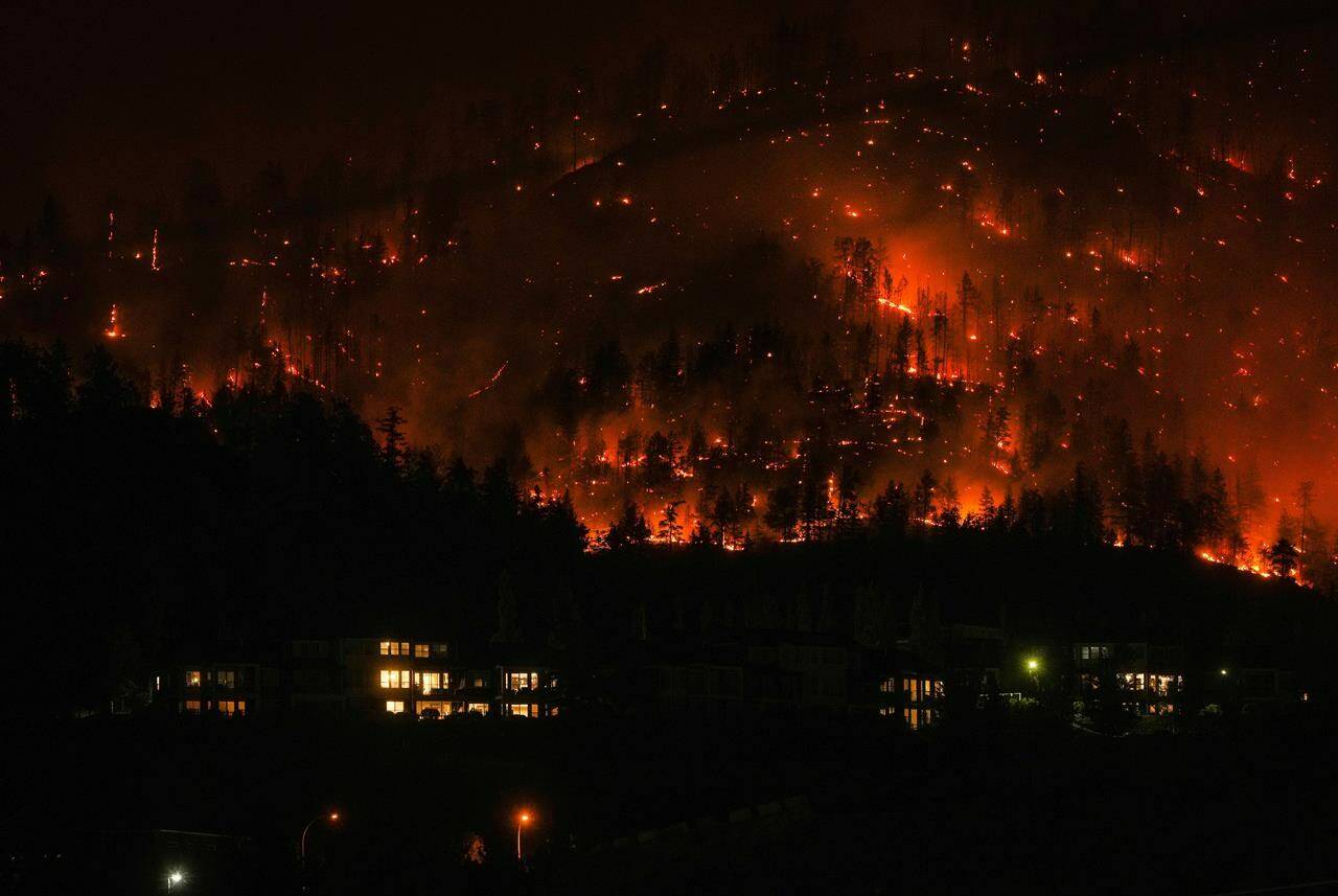 The McDougall Creek wildfire burns on the mountainside above houses in West Kelowna, B.C., on Friday, August 18, 2023. Canadian insurers are grappling with higher risk of wildfires amid a record-breaking season, and experts say rising premiums are just one part of how the industry is seeking to adapt to an ever-changing new normal. THE CANADIAN PRESS/Darryl Dyck