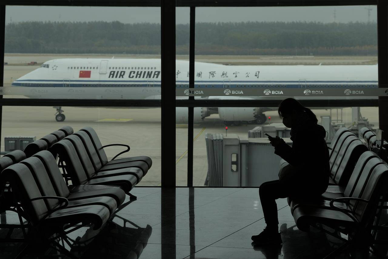 <div>Beijing and Ottawa are in talks over how to increase flights between Canada and China, following an American deal in June. A passenger checks her phone as an Air China passenger jet taxis past at the Beijing Capital International airport in Beijing, Saturday, Oct. 29, 2022. THE CANADIAN PRESS/AP-Ng Han Guan</div>